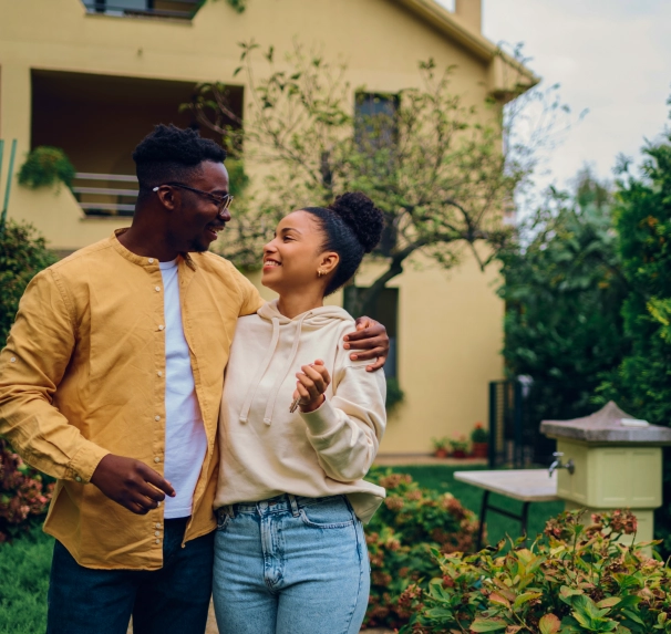 young couple smiling while standing in front of their new home