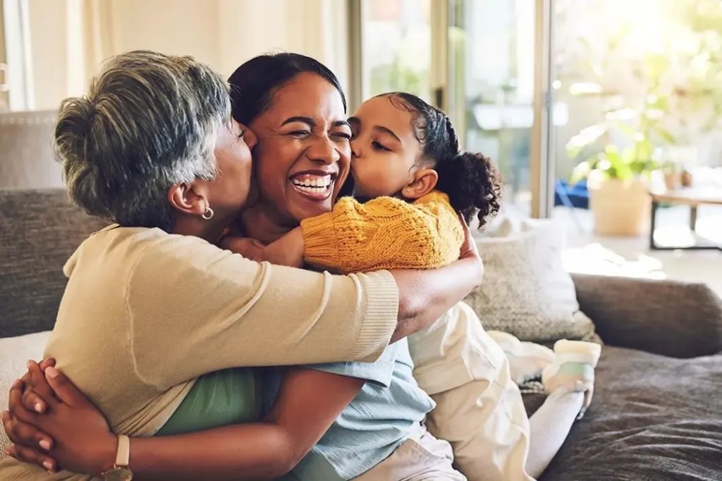 a woman is embraced lovingly by her mother and her daughter.
