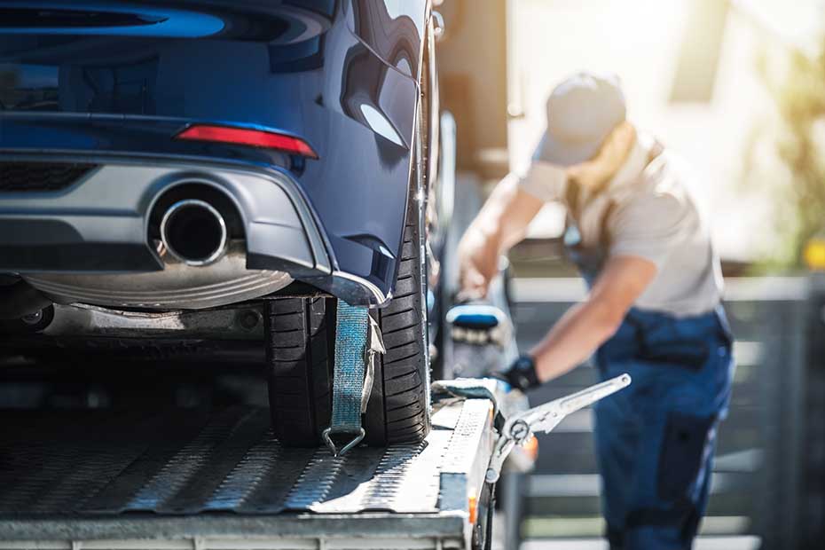 Tow truck driver loading a car.