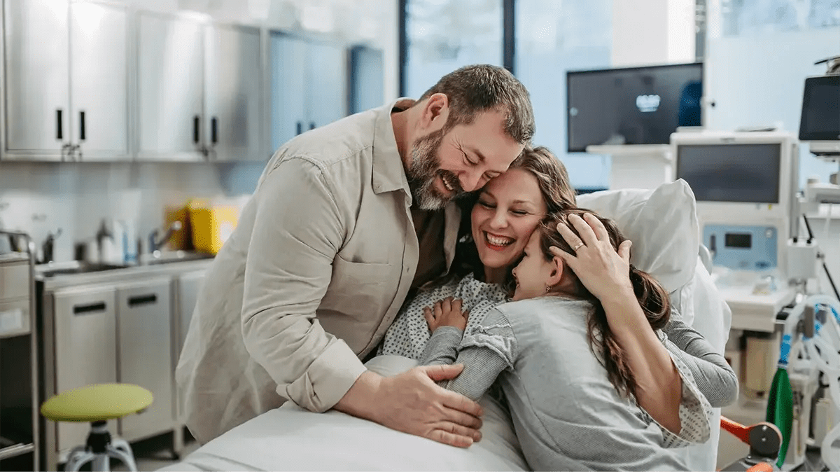 A mother recovering in hospital with her family, covered by disability insurance