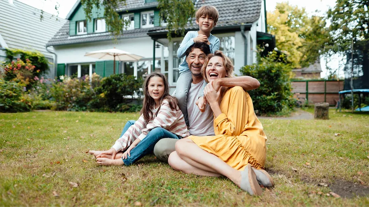 Family sitting outside their home covered by home insurance