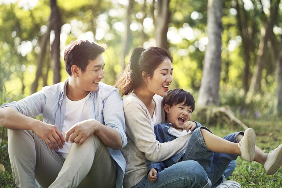 Couple and their child sitting and smiling in a park