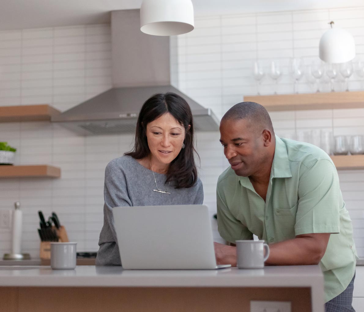 A middle-aged couple in their kitchen, reviewing RBC joint life payout annuity options for retirement income on a laptop.