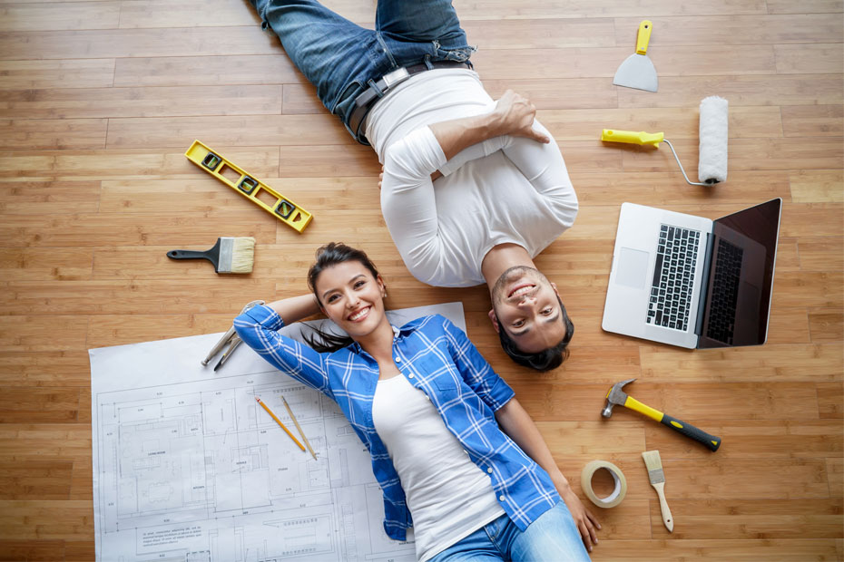 A couple laying down on floor with home maintenance equipment and smiling.