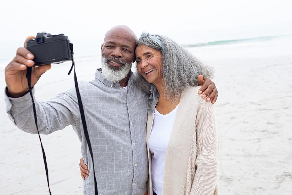 Retired couple taking a photo on the beach.