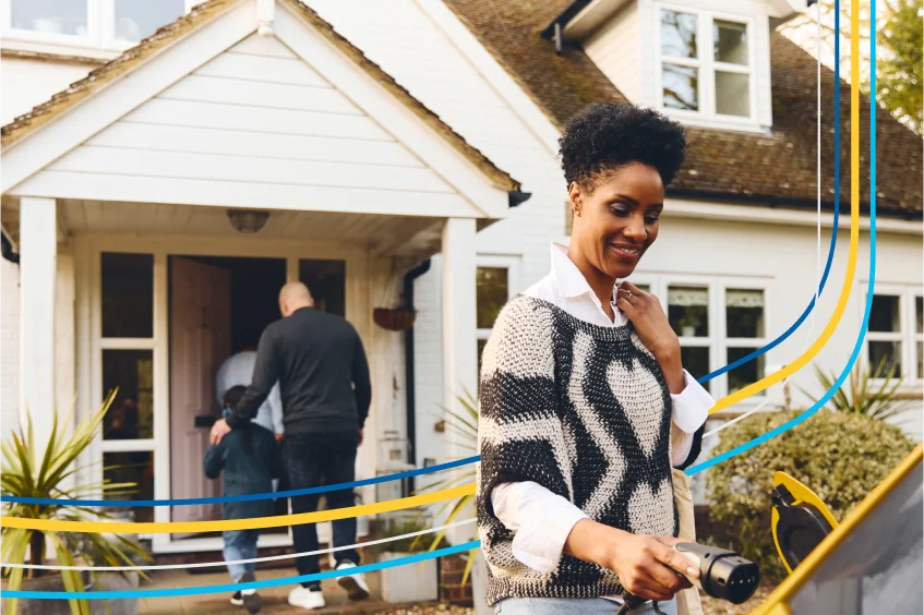 Une femme rechargeant son véhicule électrique à l’extérieur de sa maison