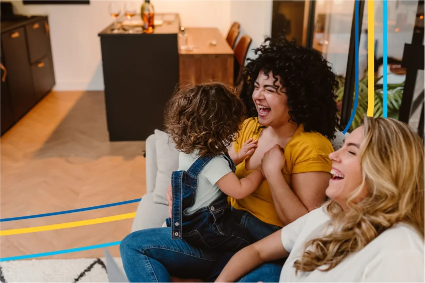 Image d’une famille installée sur un canapé qui rit ensemble