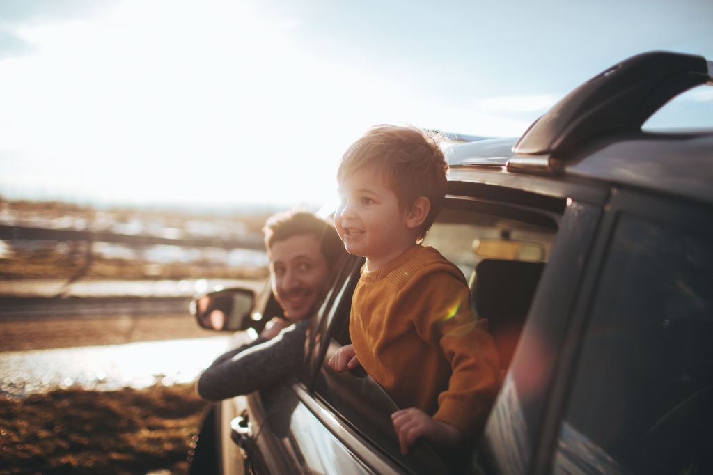 Petit garçon et son père regardant par la fenêtre d'une voiture pendant le road trip