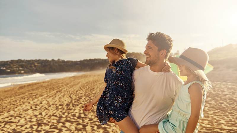 father with kids at the beach